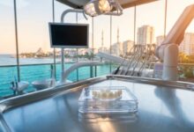 A photorealistic image of perfectly crafted porcelain veneers on a tray in a modern, high-tech dental clinic. A large window in the background shows a beautiful, blurred view of a sunny coastal city in Turkey.