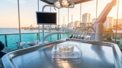 A photorealistic image of perfectly crafted porcelain veneers on a tray in a modern, high-tech dental clinic. A large window in the background shows a beautiful, blurred view of a sunny coastal city in Turkey.