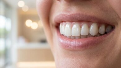 A detailed close-up of a person's perfect, bright smile, showcasing the natural and flawless appearance of well-maintained dental veneers against a soft, blurred background.