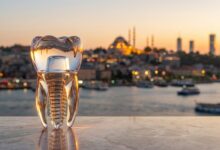 A photorealistic image showing a perfect, abstract model of a dental implant with a blurred background of the Istanbul, Turkey skyline at sunset, representing dental tourism.