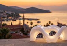 An abstract, glowing white form resembling a perfect smile is set against the beautifully blurred backdrop of a Turkish coastal city at sunset, symbolizing the fusion of dental treatment and travel.