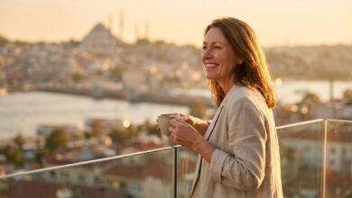 A happy British woman with a perfect smile enjoys the sunrise from a balcony with a blurred view of Istanbul, symbolizing the positive experience of dental tourism.