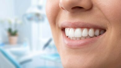 A detailed, photorealistic close-up of a person's incredibly bright, white, and healthy smile. The background is a softly blurred, modern, and clean professional setting.