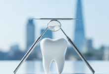 A close-up, photorealistic image showing clean, stylized dental instruments and a molar tooth arranged in distinct, layered sections on a pristine white surface, symbolizing the tiered structure of healthcare treatment. In the softly blurred background, a UK cityscape is faintly visible under bright, cool lighting, with no visible text.
