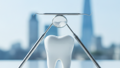 A close-up, photorealistic image showing clean, stylized dental instruments and a molar tooth arranged in distinct, layered sections on a pristine white surface, symbolizing the tiered structure of healthcare treatment. In the softly blurred background, a UK cityscape is faintly visible under bright, cool lighting, with no visible text.