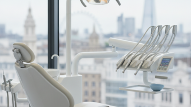 A photorealistic image of a sophisticated, modern dental treatment room in the UK. The scene features a pristine, empty ergonomic dental chair, sleek advanced dental instruments, and a soft, bright clinical light. Through a large window in the background, a very softly blurred London cityscape is visible. The image conveys a sense of cleanliness, high technology, and patient comfort, with no visible text.