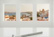 A close-up, sharp image of a modern, polished dental tool on a sterile white surface in a high-tech dental clinic. In the blurred background, a sunny Mediterranean cityscape with historical architecture is visible.