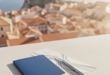 A detailed image showing a passport, a stylized boarding pass without text, and a modern dental tool resting on a clean surface, with a brightly lit, blurred European city background suggesting travel and dental care.