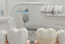 A close-up, photorealistic image comparing a durable zirconium dental crown on one tooth model and a highly aesthetic porcelain dental crown on another, set against a blurred modern dental clinic background.