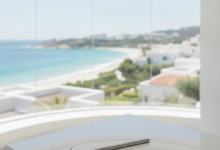 A bright, modern dental clinic interior with a large panoramic window looking out onto a beautiful, sunny Mediterranean coastal town. A polished dental mirror rests on a white counter in the foreground. The scene combines dental care and travel, free of any text.