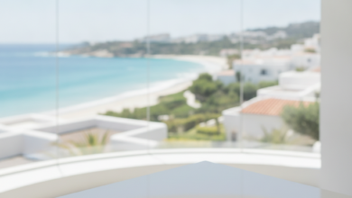 A bright, modern dental clinic interior with a large panoramic window looking out onto a beautiful, sunny Mediterranean coastal town. A polished dental mirror rests on a white counter in the foreground. The scene combines dental care and travel, free of any text.
